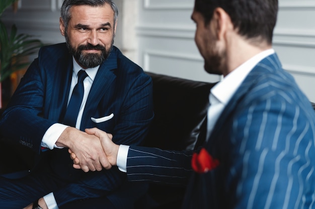 Empresários apertando as mãos, terminando uma reunião.