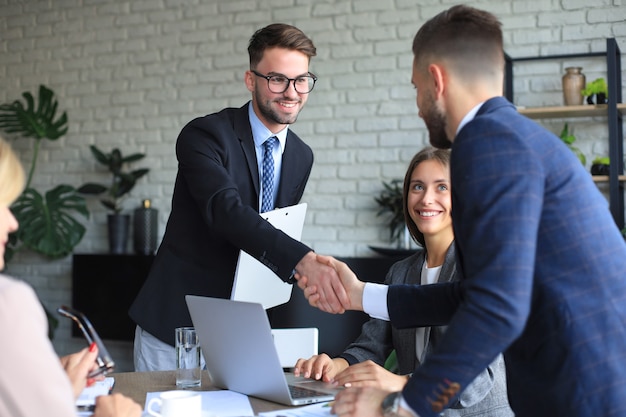 Empresários apertando as mãos, terminando uma reunião.