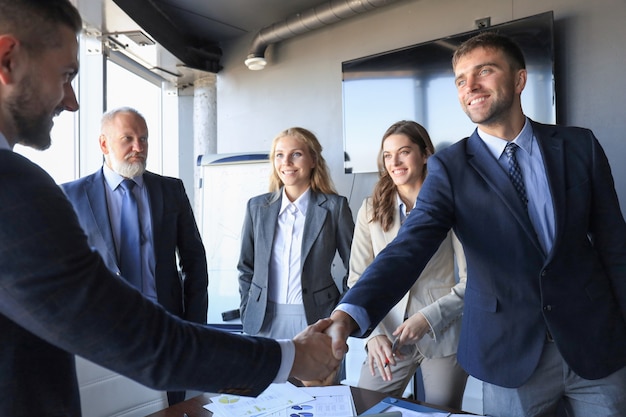 Empresários apertando as mãos, terminando uma reunião.