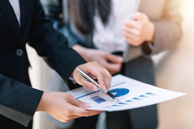 Empresários apontando e explicando gráficos gráficos e analisando planos com colegas em reunião da empresa