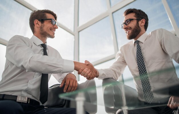 Foto empresarios de apretón de manos sentados en el vestíbulo del centro de negocios el concepto de cooperación