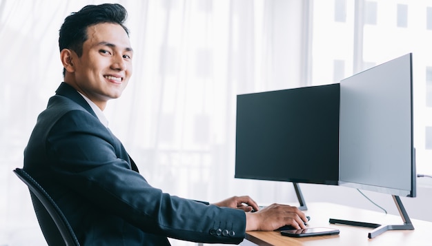 Los empresarios asiáticos se centran en trabajar. Una computadora con dos pantallas en blanco.