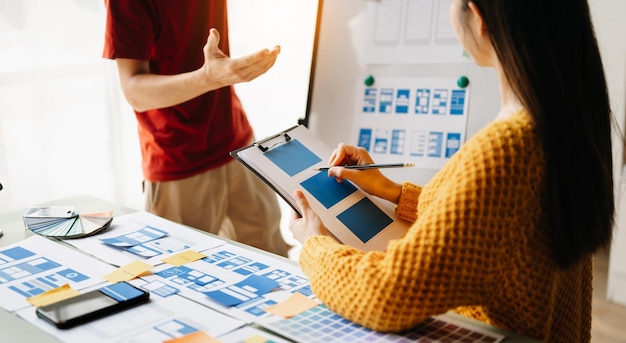 Empresarios asiáticos y mujeres que se reúnen en el cargo Lluvia de ideas de los empleados y trabajo como plan de equipo y discusión del proyecto por punto en papel y tableta