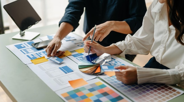 Empresarios asiáticos y mujeres que se reúnen en el cargo Lluvia de ideas de los empleados y trabajo como plan de equipo y discusión del proyecto por punto en papel y tableta