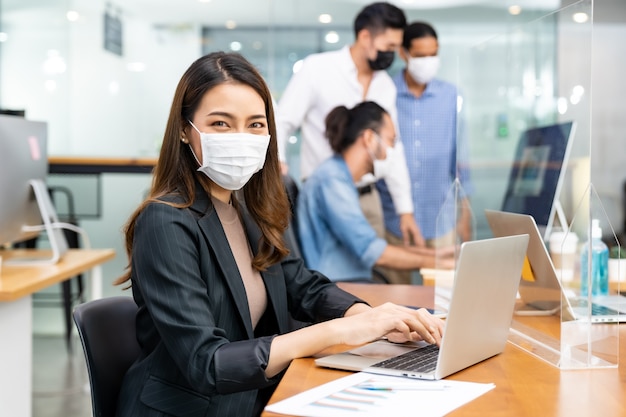 Los empresarios asiáticos que trabajan en la oficina con mascarilla protectora