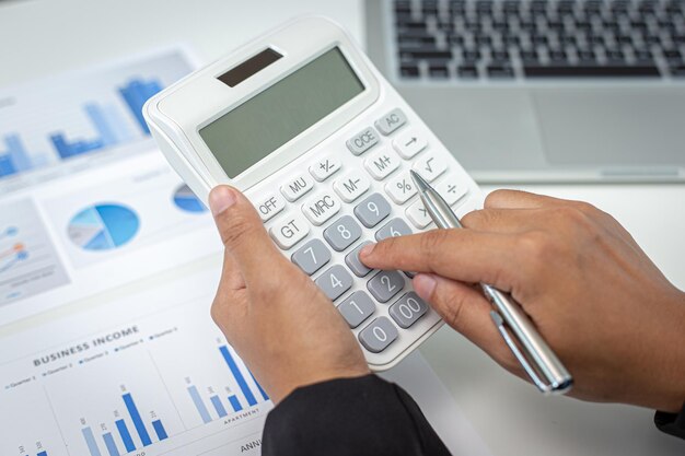 Los empresarios calculan las finanzas y analizan los datos del mercado con gráficos y computadoras portátiles en el trabajo