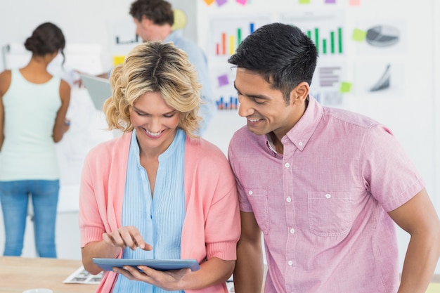 Empresários casuais usando tablet digital com colegas para trás no escritório