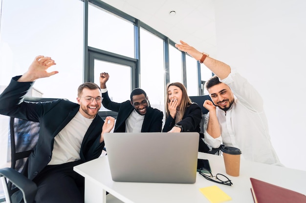 Empresarios celebrando la victoria en la oficina en la computadora portátil