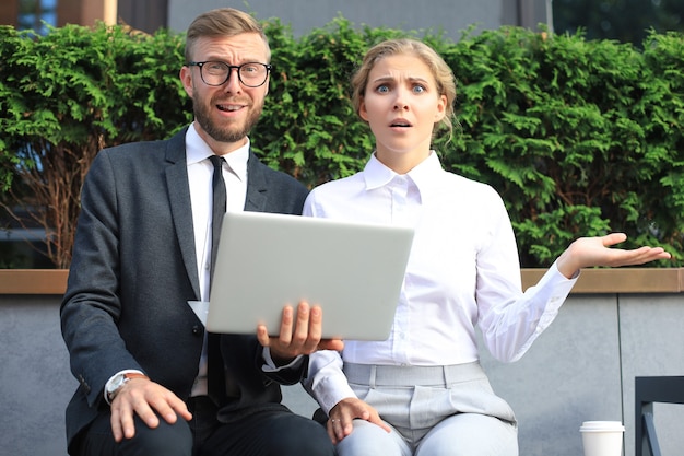 Empresários chocados com informações do laptop.