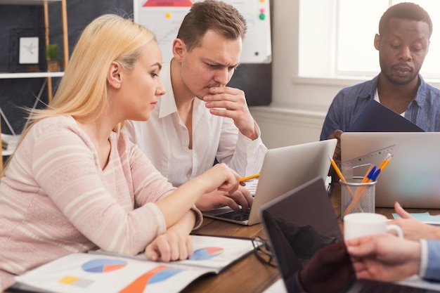 Empresários concentrados trabalhando no escritório. Equipe jovem e ocupada estudando um novo projeto ou relatório financeiro, copie o espaço