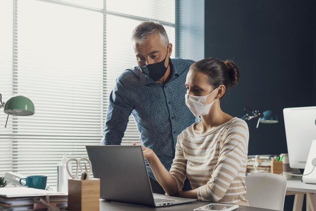 Foto empresários corporativos trabalhando juntos no escritório, conversando e usando máscaras protetoras, medidas de prevenção do coronavírus covid19