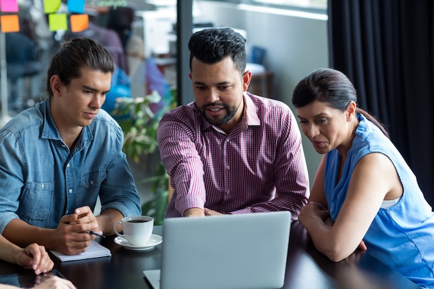 Empresarios discutiendo sobre laptop en la oficina