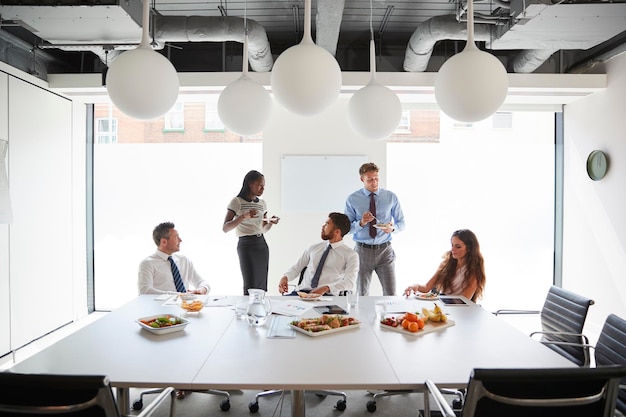 Empresários e empresárias reunidos na moderna sala de reuniões durante o almoço de trabalho