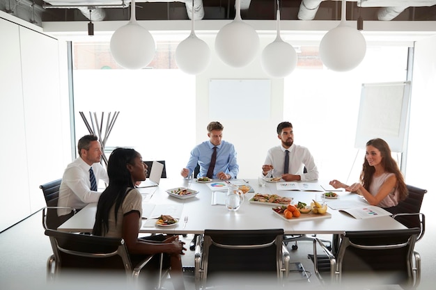 Empresários e empresárias reunidos na moderna sala de reuniões durante o almoço de trabalho