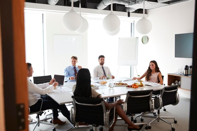 Empresários e empresárias reunidos na moderna sala de reuniões durante o almoço de trabalho