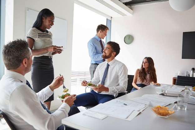 Empresários e empresárias reunidos na moderna sala de reuniões durante o almoço de trabalho