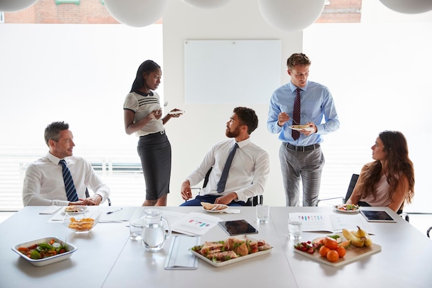 Empresários e empresárias reunidos na moderna sala de reuniões durante o almoço de trabalho