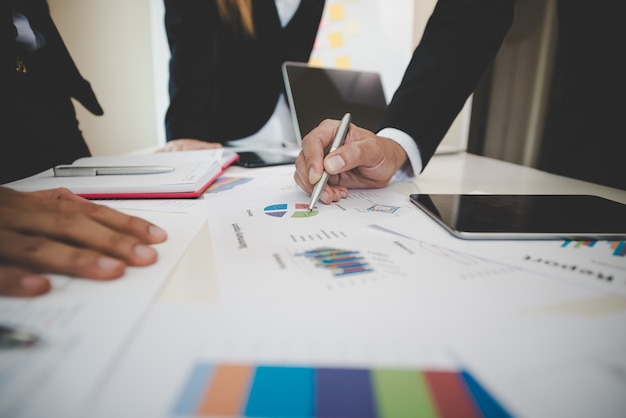 Empresários e mulher discutindo em gráficos do stockmarket na mesa de escritório