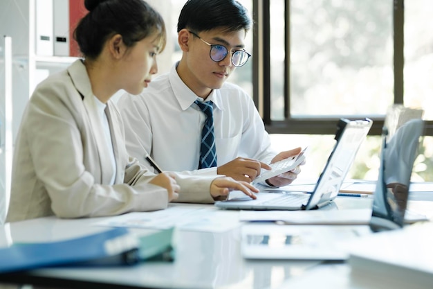 Empresários estão trabalhando discutindo e analisando seu projeto usando laptop e gráficos