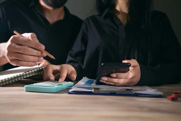 Empresários estão usando telefone celular e calculadora na mesa de trabalho