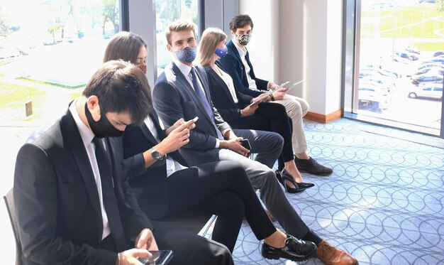 Empresarios estresantes esperando entrevista de trabajo con mascarilla, cuarentena de distanciamiento social durante el efecto COVID19.