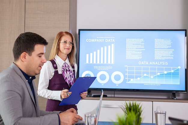 Empresarios exitosos y gente de negocios en la sala de conferencias analizando gráficos y diagramas en un televisor. Personas de negocios exitosas