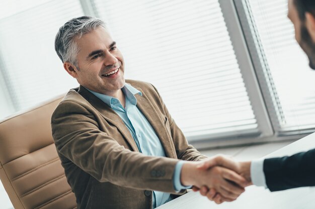 Los empresarios felices apretón de manos en la oficina