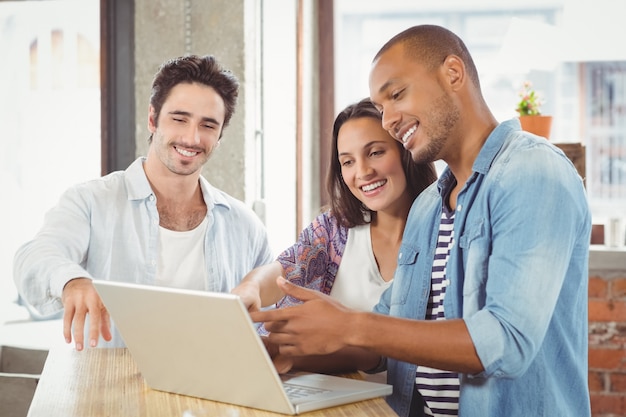 Foto empresários felizes apontando para laptop no escritório