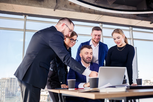 Empresários felizes olhando para a apresentação do laptop, sucesso no trabalho, sentado em um escritório moderno. Negociações online de sucesso. Empresários compartilham seus conhecimentos