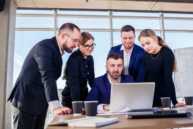 Empresários felizes olhando para a apresentação do laptop, sucesso no trabalho, sentado em um escritório moderno. Negociações online de sucesso. Empresários compartilham seus conhecimentos