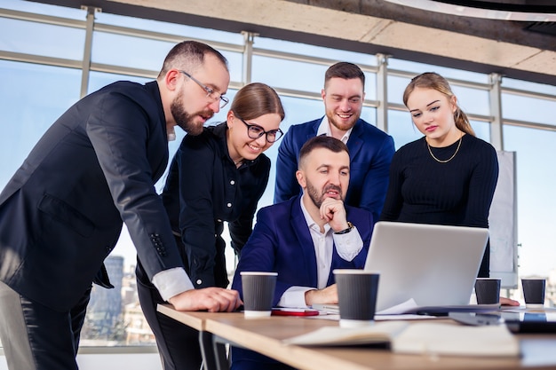 Empresários felizes olhando para a apresentação do laptop, sucesso no trabalho, sentado em um escritório moderno. negociações online de sucesso. empresários compartilham seus conhecimentos