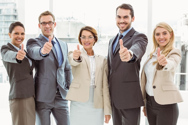 Empresarios gesticular pulgares arriba en la oficina