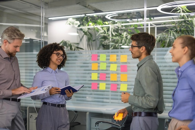 Empresarios hablando en su equipo diverso durante una sesión de lluvia de ideas con notas adhesivas