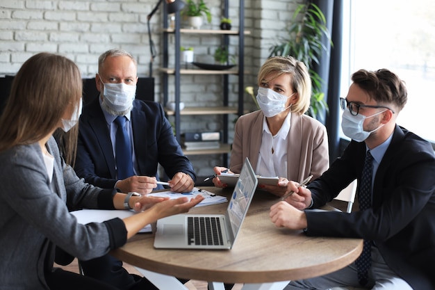 Empresarios con máscaras protectoras mientras realizan una presentación en una reunión durante la epidemia de coronavirus.