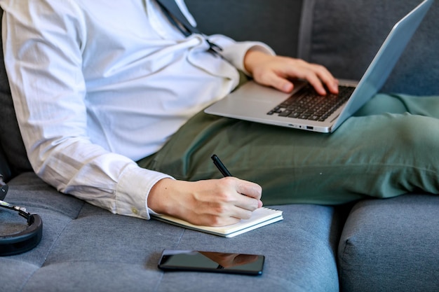 Empresários modernos se deitam no sofá do saguão para relaxamento casual esticando as pernas e trabalhando com laptops confortáveis para comunicação on-line