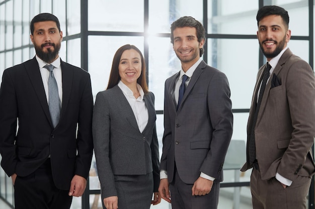 Empresarios con morena en grupo posando en el vestíbulo de la oficina