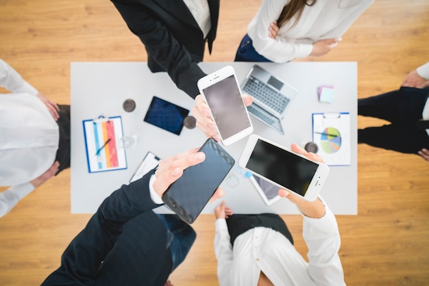 Los empresarios muestran teléfonos inteligentes en el fondo del escritorio. vista desde arriba