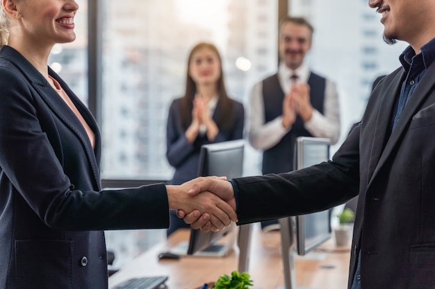 Empresarios y mujer de negocios dándose la mano durante una reunión con llegar a un acuerdo para los negocios