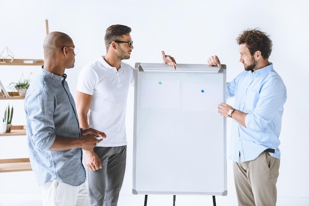 Foto empresários multiculturais discutindo novas estratégias de negócios no quadro branco no escritório