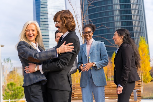Empresários multiétnicos de meia-idade e empresárias se abraçando entre colegas de trabalho