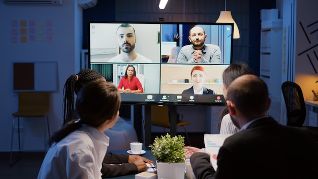 Foto empresarios multiétnicos discutiendo las estadísticas de la empresa con compañeros de trabajo remotos