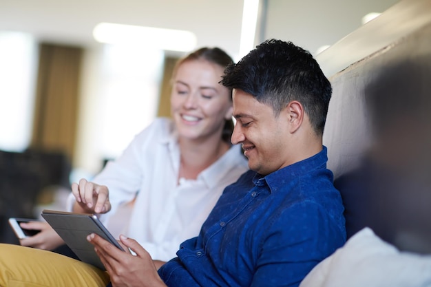 empresários multiétnicos homem indiano com uma colega trabalhando juntos no computador tablet na área de relaxamento do escritório de inicialização moderno