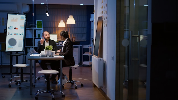 Foto empresarios multiétnicos que trabajan horas extraordinarias en la sala de reuniones de la oficina