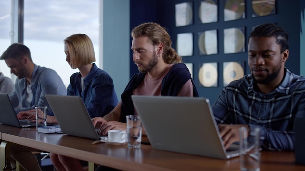 Empresários multiétnicos que trabalham com computador portátil no escritório moderno