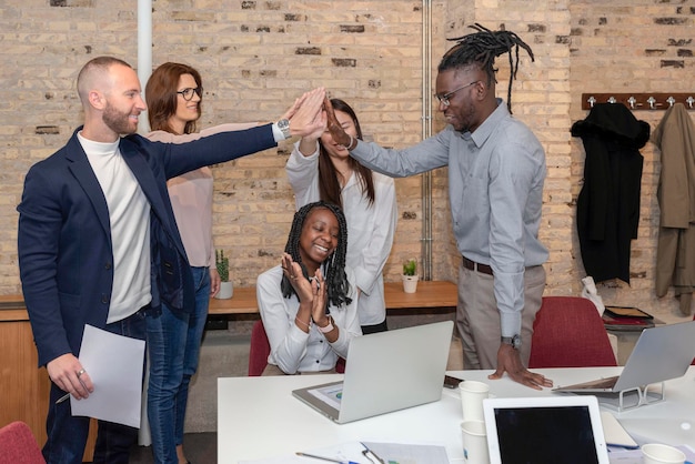 Foto empresários multirraciais na sala de conferências alcançam o sucesso corporativo comemorando a conquista