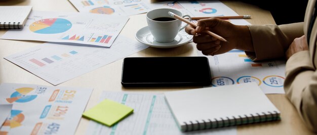 Empresarios no identificados irreconocibles sostienen lápiz en mano trabajo con gráfico gráfico crecimiento objetivo de empresa y documentos de papel de estrategia financiera en escritorio con tableta de pantalla táctil y portátil.