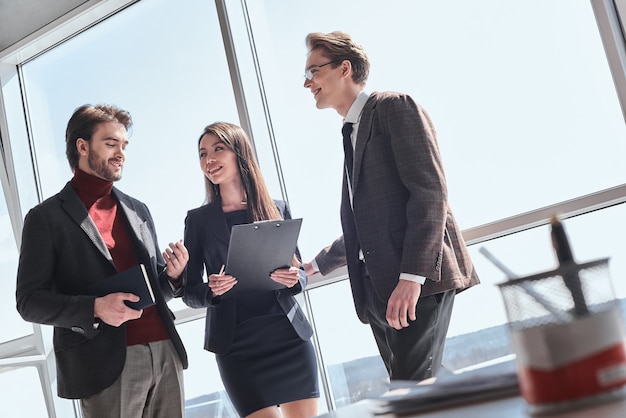 Los empresarios en la oficina trabajando juntos de pie discutiendo pr