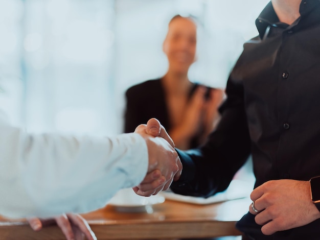 Empresários ou advogados apertando as mãos terminando reuniões ou negociações em escritórios ensolarados. Aperto de mão e parceria de negócios