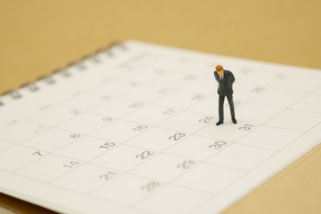 Empresarios de personas en miniatura en calendario blanco