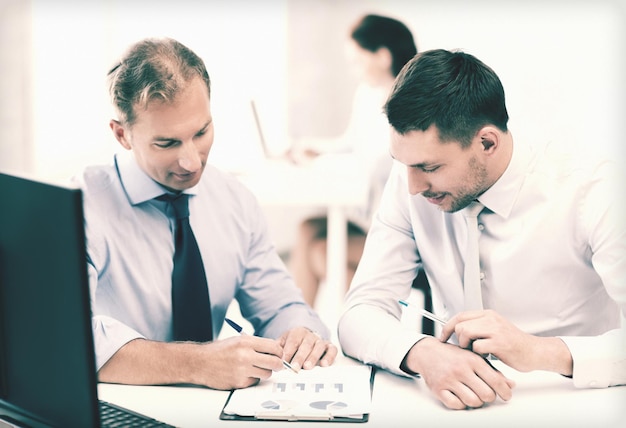 empresarios con portátil discutiendo gráficos en reunión